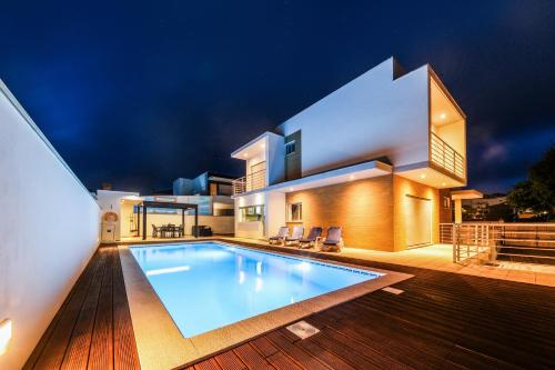 a villa with a swimming pool in front of a house at Nazare House4you in Nazaré