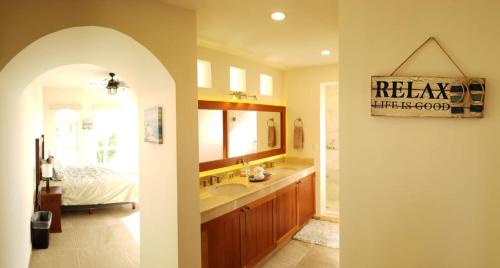 a bathroom with a sink and a bed and a mirror at Experience Luxury on Isla Mujeres! in Isla Mujeres