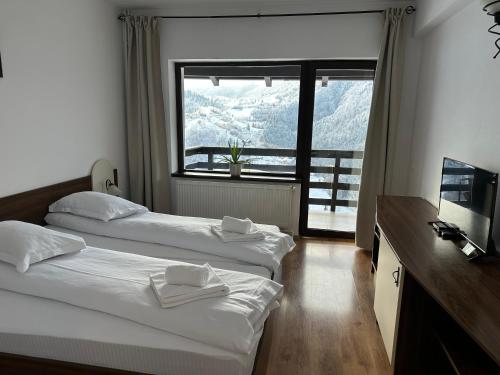 a hotel room with two beds and a large window at Pensiunea Magura in Măgura