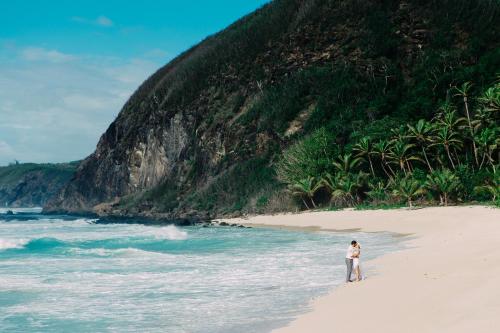 a man standing on a beach next to the ocean at Yasawa Island Resort & Spa in Mbukama