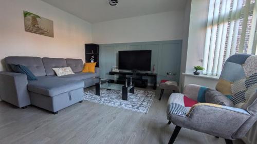 a living room with a couch and chairs and a television at Leeds City Junction in Beeston Hill