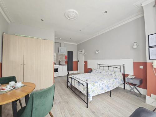 a bedroom with a bed and a table and a kitchen at Avis Hotel in Bromley