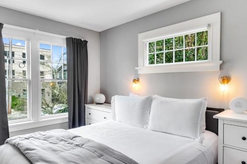 a bedroom with a white bed and two windows at Montlake Hideaway in Spite House in Seattle