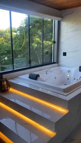a bathroom with a tub with a large window at Cabana Espelho da Lua in Itá