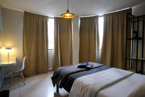 a bedroom with a bed and a desk and windows at Comfortable One Bedroom Apartment Casa Icacos # 0 in Mexico City