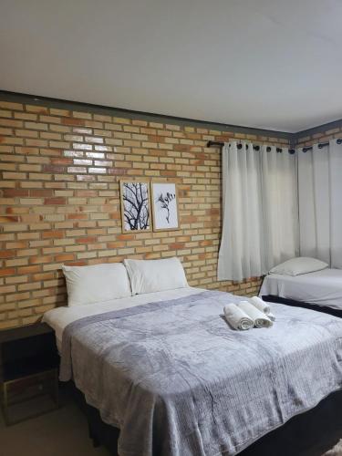 a bedroom with a large bed and a brick wall at Pousada Flor do Café in Ubajara