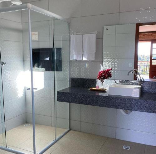 a bathroom with a glass shower and a sink at Pousada Flor do Café in Ubajara