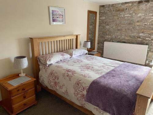 a bedroom with a bed and a stone wall at Ffyllon Fawr in Henfynyw Upper