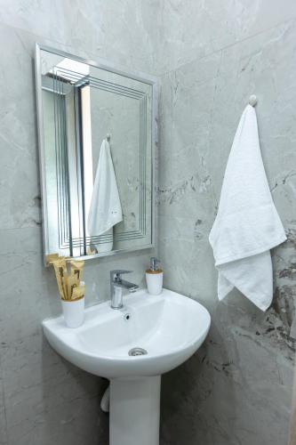 a white bathroom with a sink and a mirror at Myasnikyan Suites in Gyumri
