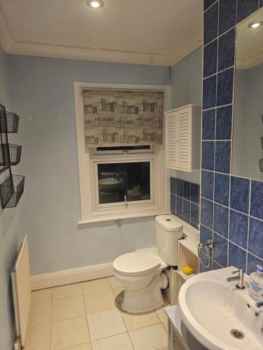 a bathroom with a toilet and a sink and a window at Stylish Guest House in heart of Dartford Central in Dartford