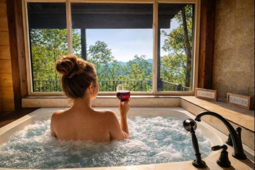 a woman in a bath tub holding a glass of wine at Gatlinburg Amazing Views-EV Chrger - Firepit, Spa Shower and Jacuzzi,Hot Tub in Gatlinburg
