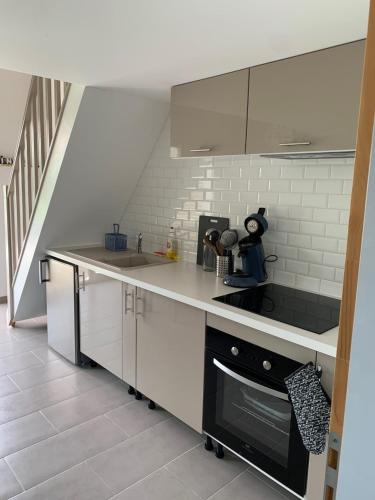 a kitchen with white cabinets and a black oven at Maisonnette Bassin d'Arcachon in Mios