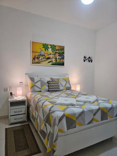 a bedroom with a bed with a yellow and gray bedspread at Pousada da Drica in Saquarema
