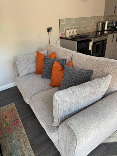 a gray couch with orange pillows in a living room at Goldie's Retreat in Blackrod