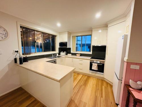 a kitchen with white cabinets and a clock on the wall at Shell Shack in Tomakin