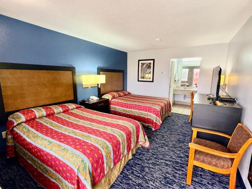 a hotel room with two beds and a television at Scottish Inns Westcott Street in Houston