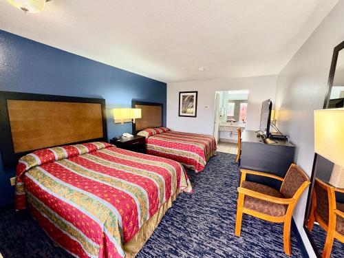 a hotel room with two beds and a chair at Scottish Inns Westcott Street in Houston