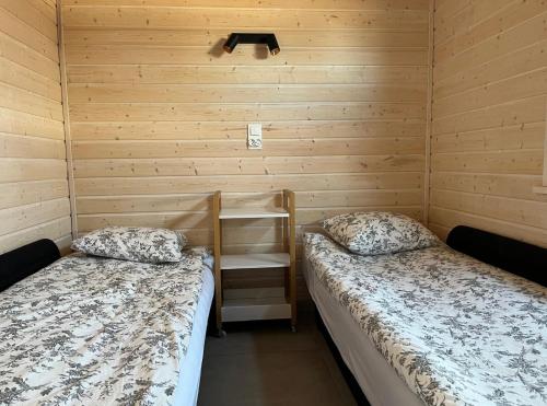 two beds in a room with wooden walls at Domki BAMBINO in Sarbinowo