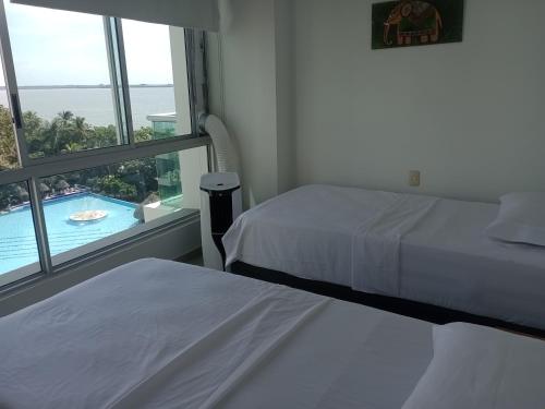 two beds in a room with a view of a pool at Costa Azul Apto603 in Playa Dormida