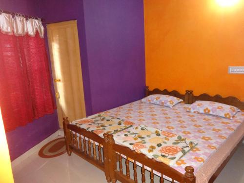une chambre avec un lit aux murs violets et orange dans l'établissement Four Seasons Home Stay (1BDH), à Madikeri