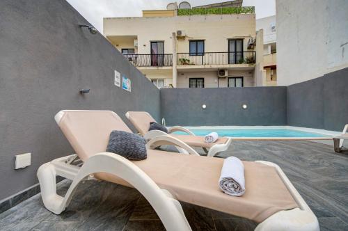 a group of chaise lounges on a patio with a pool at Central Oasis with Private Pool and Lounge Area in Santa Vennera