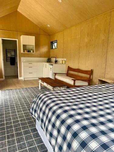 a bedroom with a bed and a bench and a kitchen at Hikuai Hideaway in Hikuai