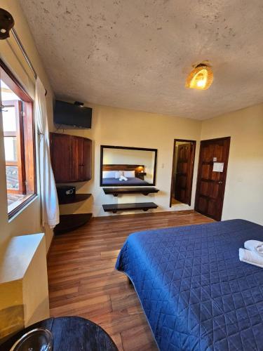 a bedroom with a blue bed and a flat screen tv at Arte Sano Hotel San Cristobal in San Cristóbal de Las Casas