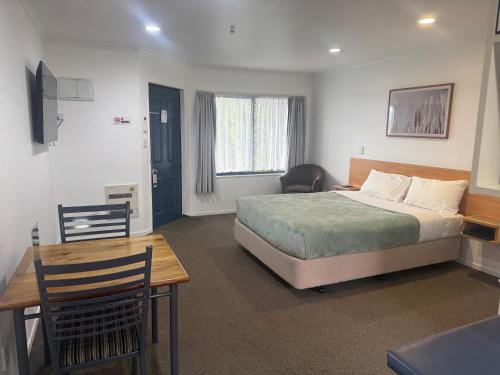 a bedroom with a bed and a table and a desk at Bassingers Motor Lodge in Levin