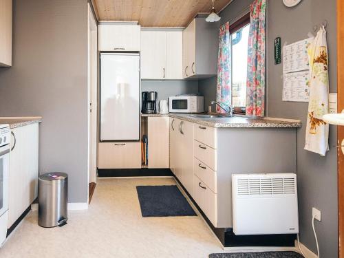 a small kitchen with white cabinets and a refrigerator at 4 person holiday home in Juelsminde in Snaptun