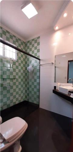 a bathroom with a toilet and a sink and a mirror at Pousada da Nona in Barretos
