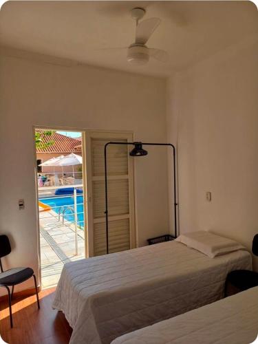 a bedroom with two beds and a view of a pool at Pousada da Nona in Barretos