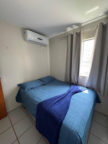 a bedroom with a bed with a blue blanket and a window at Apartamento confortável in São Luís