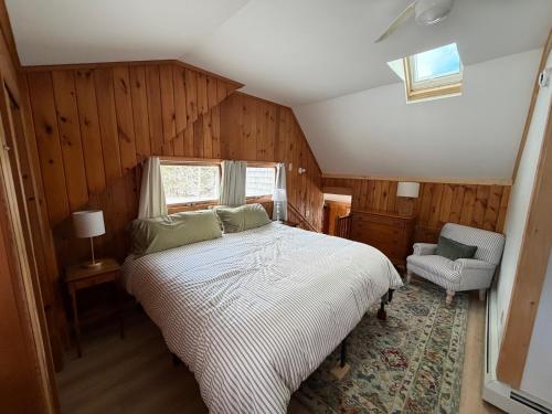 a bedroom with a bed and a chair and a window at Barnacle - quiet family Maine waterfront getaway in Orrs Island