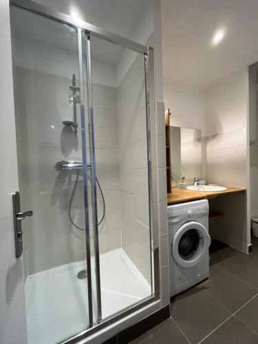 a bathroom with a shower and a washing machine at Ptit Savoy in Saint-Nectaire