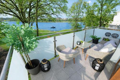 a balcony with chairs and a table with a view of a river at River View - widok na wodę, parking w hali, winda, 3pok i 5 łóżek, klima, Netflix i Max, centrum in Iława