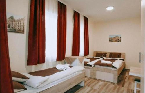 two beds in a room with red curtains at Evropa Sombor in Sombor