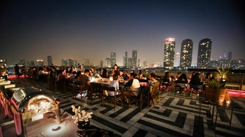 a group of people sitting at tables on a rooftop at Hotel Once Bangkok in Bangkok