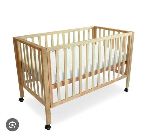 a wooden crib with casterlled legs and white cribding at Scenic Lanka rooms in Dehiwala