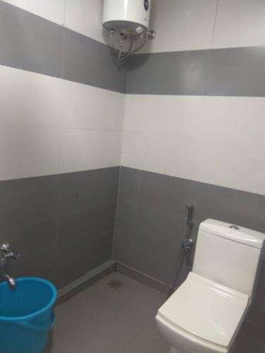 a bathroom with a white toilet and a blue bucket at River Valley Huts, Wayanad in Panamaram