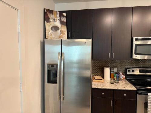 a stainless steel refrigerator in a kitchen with black cabinets at Experience the Best of Fort Worth Stylish Apartment in the Cultural District in Fort Worth