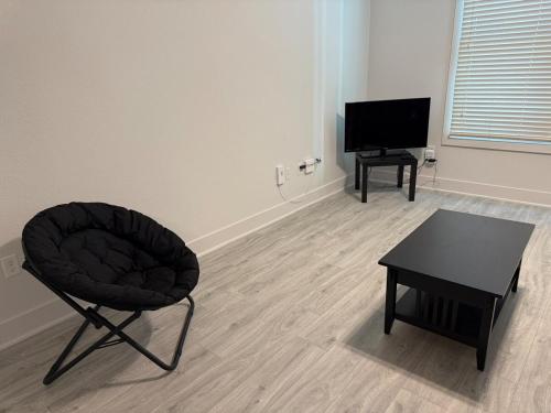a room with a chair and a table and a television at Experience the Best of Fort Worth Stylish Apartment in the Cultural District in Fort Worth