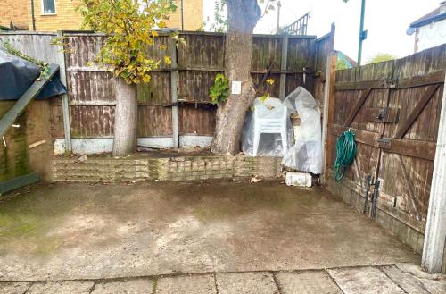 a backyard with a fence and a chair next to a tree at Kate House in London
