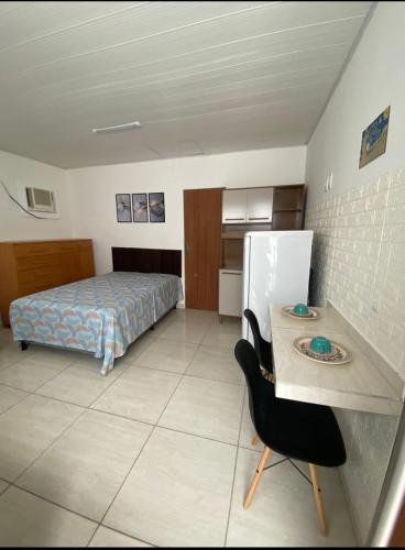 a bedroom with a bed and a table and a chair at ML Integra Mix kitnets in Maceió