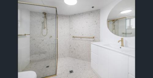 a white bathroom with a shower and a sink at Hi Surf Beachfront Resort Apartments OFFICIAL SITE in Gold Coast
