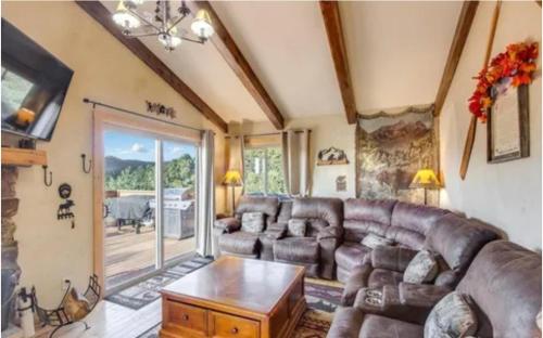 a living room with a leather couch and a table at Rocky Mountain Panorama Cabin in Estes Park