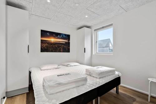 a white bedroom with two beds and a window at 9951-Hvide-Sande-Langsand-206 in Hvide Sande