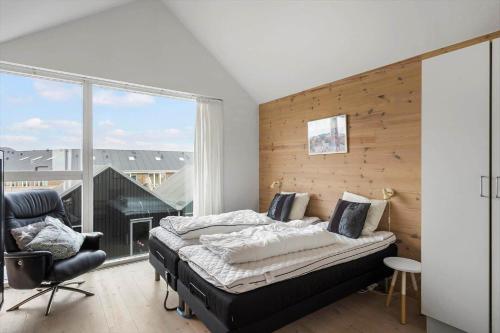 a bedroom with a bed and a chair and a window at 719-Hvide-Sande-Slusen-19 in Hvide Sande