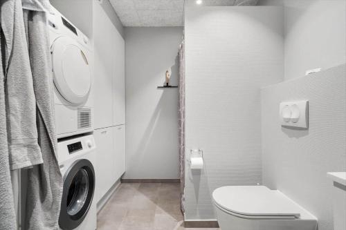 a white bathroom with a washing machine and a toilet at 776-Hvide-Sande-Norregade-2-nr-27 in Hvide Sande