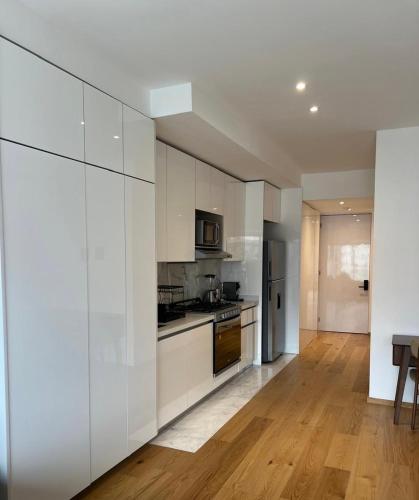 a kitchen with white cabinets and a wooden floor at Luxury Apartment in Roma Norte With Stunning Views in Mexico City