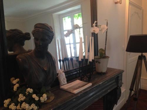 a statue of a woman sitting on a fireplace with candles at Les Chambres d'Hôtes du Bois Joli in Semur-en-Auxois